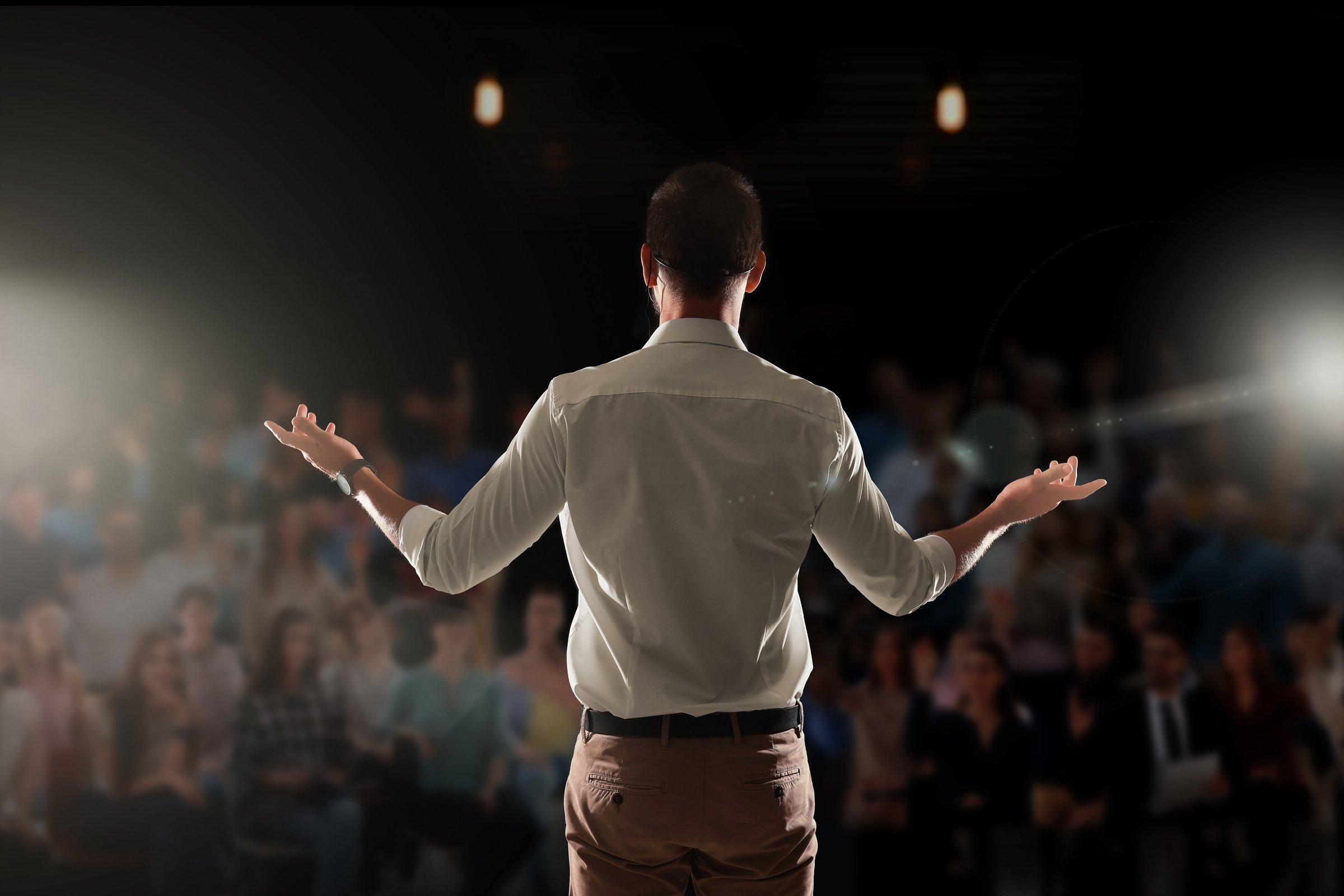 Motivational Speaker with Headset Performing on Stage, Back View